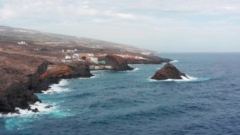 4K drone aerial shot of Los Roques village, Playa El Abrigo, Atlantic Ocean and volcanic cliffs in south Tenerife, Canary Islands