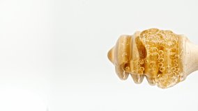 Honey Dripping to a Honey Dipper. Liquid Honey Flows on the Isolated White Background. Healthy Food Concept. Vertical video. Macro Shot.