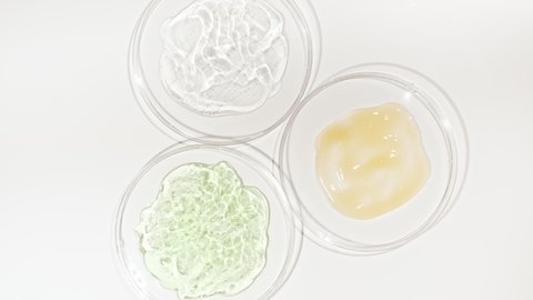 Rotation of Petri dishes with cosmetics samples on a white background. Transparent Gel Fluid, Serum, Cream with Bubbles. Chemical laboratory research. Natural Organic cosmetics, medicine.