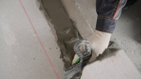 The worker applies the mortar to the floor with a notched trowel. The repairman cut with a trowel, applying the adhesive mixture for the aerated concrete block. Construction and repair laying using to