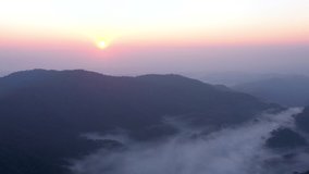 Drone flies over the sea fog that covers the valley mountains in morning light. Filmed 4k, video.
