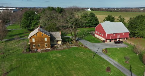 Rural American farm scene. Two story log cabin family home and red barn in spring setting in USA. Agriculture community.