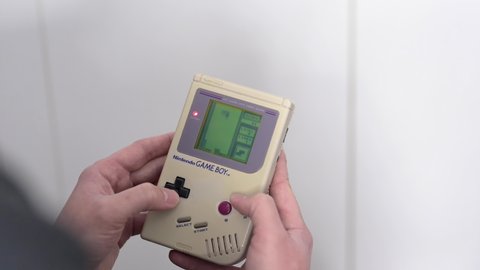 Madrid, Spain; 04-04-2022: 4k video of a man holding in his hands a classic video game Nintendo Game Boy while playing the popular game Tetris