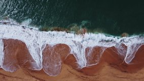 Sea coast, view from the height. Yellow sandy beach with blue sea. A deserted beach with a bird's eye view. Sea waves roll on the sandy beach. Beautiful sea landscape. Ocean, waves, sand. Aerial