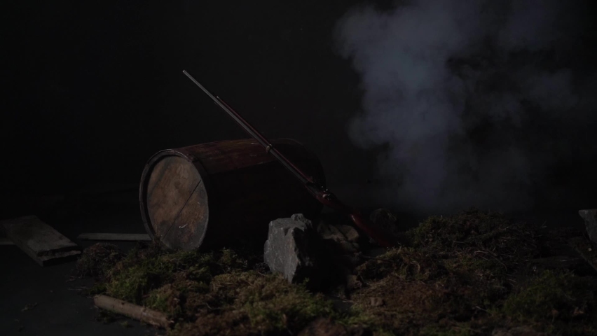 Ancient musket on a barrel among the smoke on the battlefield