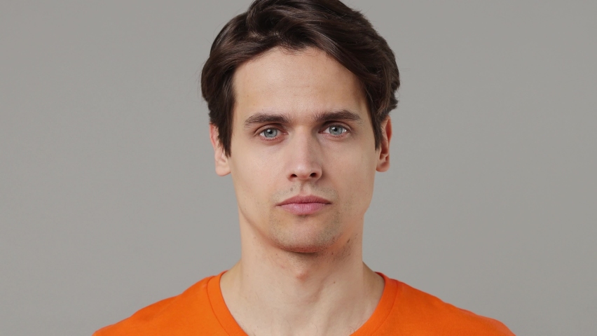 Close up shocked surprised stupefied young brunet man 20s years old wears orange t-shirt looking camera say wow omg no way keep mouth wide open isolated on plain grey wall background studio portrait Royalty-Free Stock Footage #1088984223