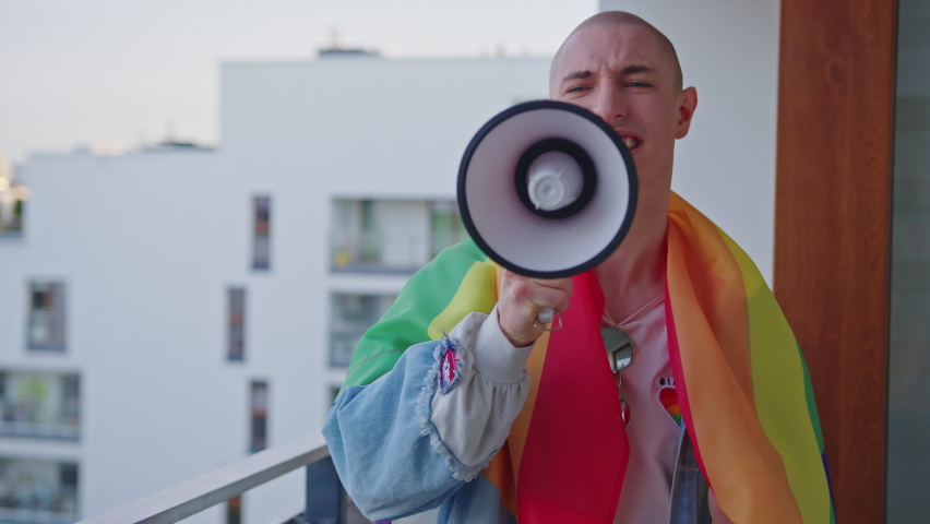 queer gay person screaming in ager and fighting for their rights with rainbow flag on shoulders. High quality 4k footage