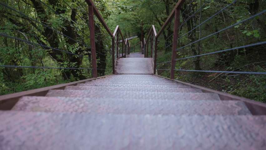 Going down the suspension metal stairs in the natural park. Slow motion, dolly shot.
