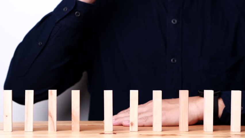 Businessman hand stopping continuous failing domino wooden effect. Concept of Risk Management, Business Crisis, Domino Effect, Investment, Finance, Risk, Disaster, Protection, Prevention, Opportunity Royalty-Free Stock Footage #1088988699
