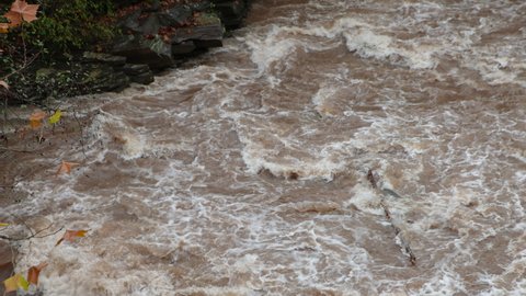 Muddy Brown River Waves Crashing by Bridge and Rocky Shore in Upstate New York