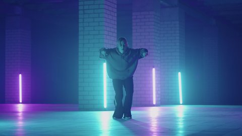 A steel woman dances hip-hop freestyle in a modern style in a hall with neon light in purple blue colors. Female Professional Hip Hop Dancer