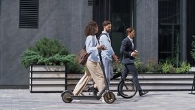 Two colleagues going downtown street talking. Shared eco-friendly transportation. Focused woman holding electric scooter commute to office with business man coworker with bicycle. Modern city mobility - Powered by Shutterstock - Get 15% off with code: PIKWIZARD15