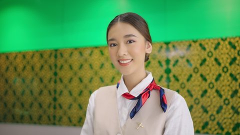 Asian female airline worker stewardess in aviation air hostess uniform looking at camera and smiling.