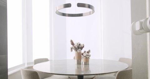 Minimalist Modern White Dining Room with white chairs and minimalist lamp. Minimalist Dining Table. luxury kitchen in modern style, White Simple Modern Interior. Elegant table and chairs. Dinner.
