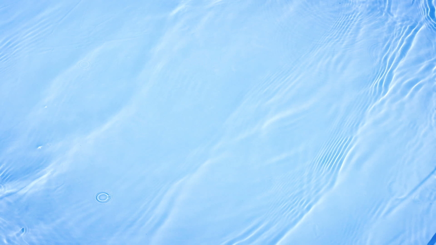 Blue clean water swimming pool reflecting the sun ripples and wave in slow motion, water wave texture background, waving water surface in 4K
