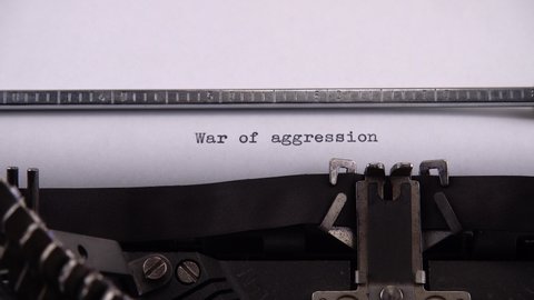 Typing phrase "War of aggression" on retro typewriter.