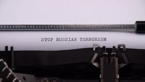 Typing phrase "STOP RUSSIAN TERRORISM" on retro typewriter.