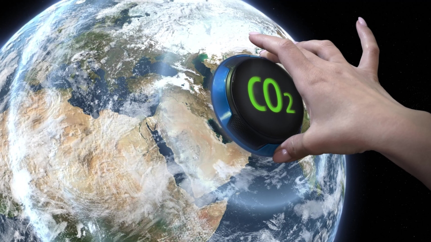 The hand turns the earth handle regulator and reduces CO2 emissions. Idea concept of reducing carbon footprint.
