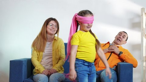 happy family at home. parents and child a playing blindfold game. happy family playing together at home. mom dad and fun daughter play blindfold game. kid dream happy family together at home concept