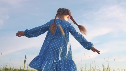 child girl a dancing in the field park. happy childhood family friendship concept. girl kid whirls in a blue dress in grass in the summer park. daughter in dancing whirls sun in the summer in nature