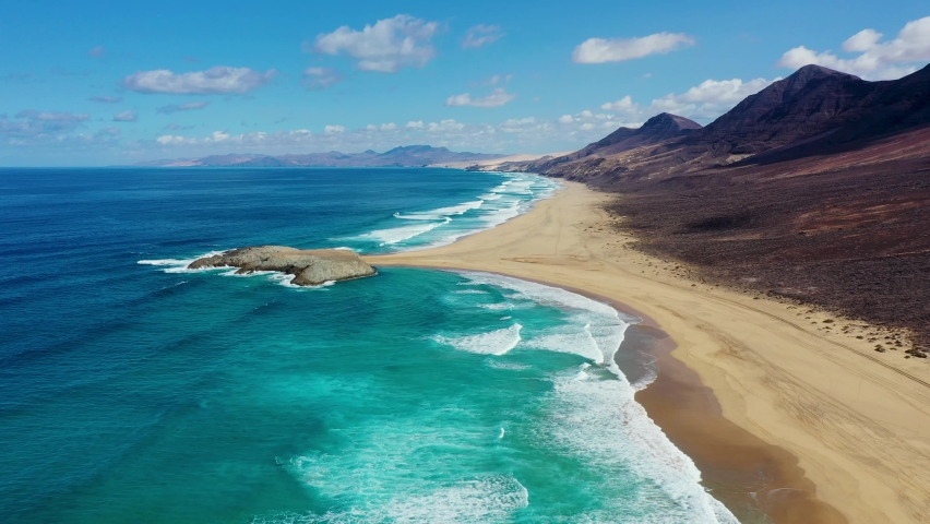 Amazing Cofete beach with endless horizon. Volcanic hills in the background and Atlantic Ocean. Cofete beach, Fuerteventura, Canary Islands, Spain. Playa de Cofete, Fuerteventura, Canary Islands. Royalty-Free Stock Footage #1089001041