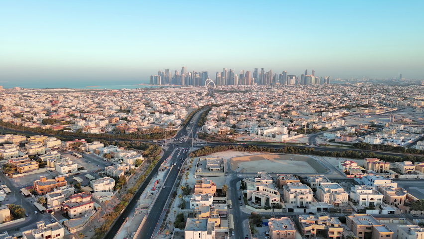 Doha, Qatar: Aerial view of capital city of Qatar at sunset, cityscape with skyscraper skyline of West Bay site on horizon - landscape panorama of Arabian Peninsula from above, West Asia Royalty-Free Stock Footage #1089001419