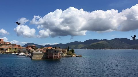 Panoramic view from port of Portoferraio village of green coast of Elba island and beautiful white clouds and seagulls , Livorno, Tuscany, Italy.