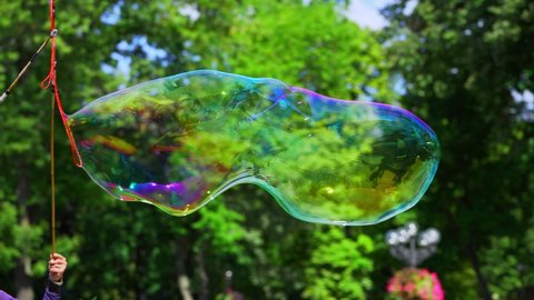 large multicolored soap bubbles on a background of green trees and blue sky. rainbow colors on flying soap bubbles. holiday for happy children. magic, dreams. 