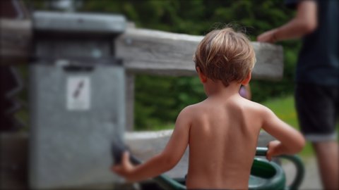 Little boy holding watering can outside at garden wearing underwear