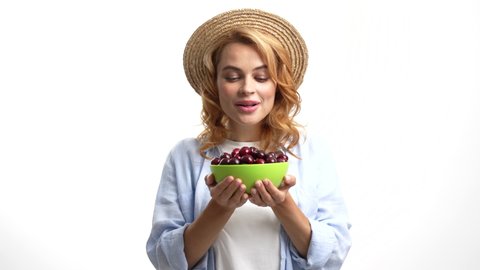 positive woman in straw hat smelling fresh ripe sweet cherry berry, selective focus, seasonal fruit
