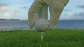 Hand in glove placing golf ball on tee - Powered by Shutterstock - Get 15% off with code: PIKWIZARD15