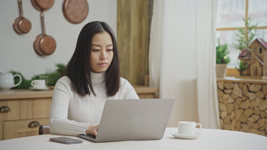 Young adult woman working focused on a laptop computer in a scandinavian apartment
