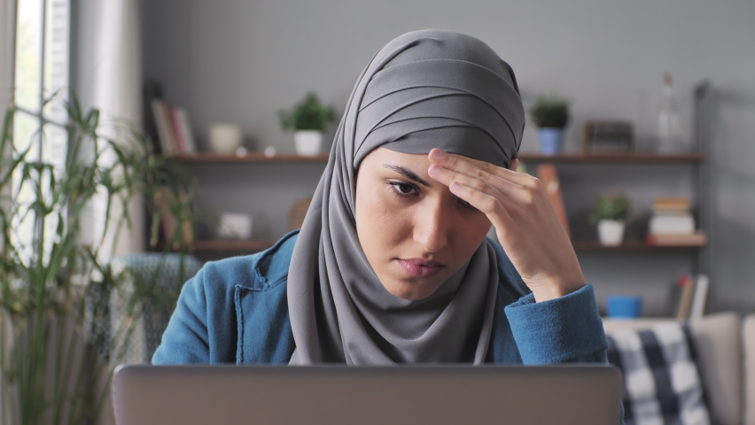 muslim female entrepreneur upset stressed sits at the desk working at computer reading bad news,arab woman works at the laptop frustrated having problem Royalty-Free Stock Footage #1089006409
