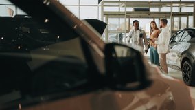 Competent car dealer using digital tablet for work with clients at showroom. Multiracial couple talking with manager while buying car at dealership center. Talking with manager. Translation: Thank you - Powered by Shutterstock - Get 15% off with code: PIKWIZARD15