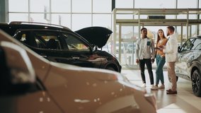 Competent car dealer using digital tablet for work with clients at showroom. Multiracial couple talking with manager while buying car at dealership center. Talking with manager. Translation: Thank you - Powered by Shutterstock - Get 15% off with code: PIKWIZARD15
