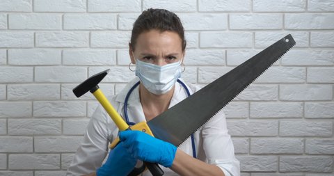 Doctor with construction tool. A view of dangerous doctor in white uniform with construction saw in hand in the cabinet.