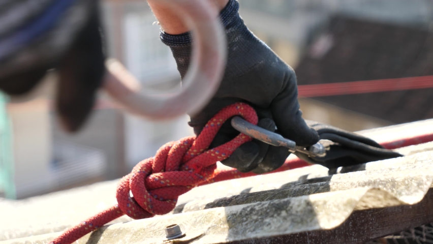 Worker hands securing life rope in a construction site roof closing a carabiner Royalty-Free Stock Footage #1089009023