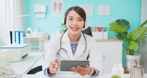 telemedicine concept - close up of asian female doctor wearing headset and using digital tablet has video chat to you in hospital