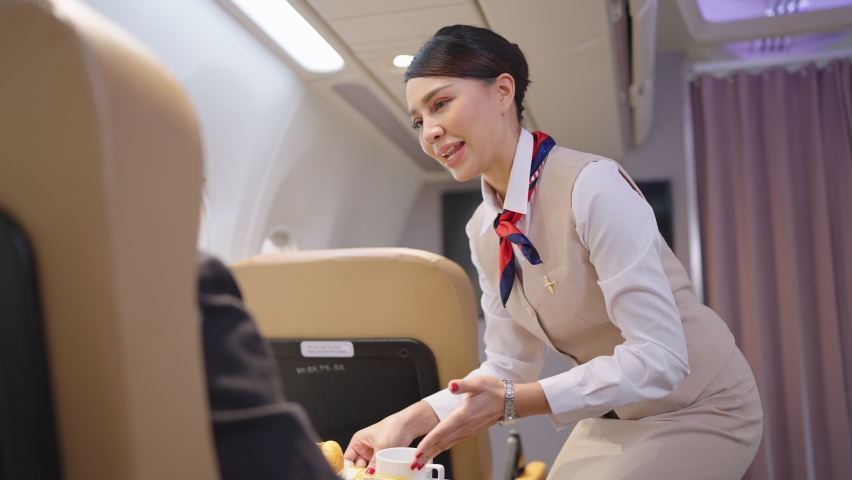 Friendly Asian female flight attendant serving food drink and talking to passengers on airplane. Airline service. | Shutterstock HD Video #1089011111
