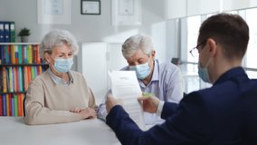 Senior couple in safety mask signing on document in real estate agent office. Finance specialist wearing protective mask sign contract with aged man and woman - Powered by Shutterstock - Get 15% off with code: PIKWIZARD15