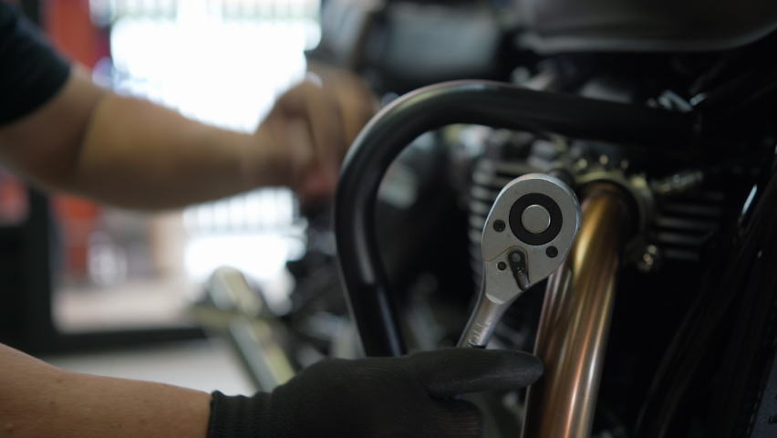 Mechanic using a wrench and socket on cylinder head of a motorcycle .maintenance,repair motorcycle concept in garage .selective focus Royalty-Free Stock Footage #1089015145