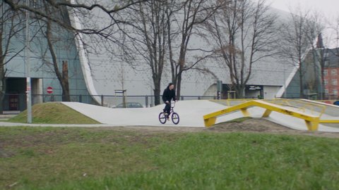TRACKING Caucasian teenager kid riding his BMX bicycle in a skate park. Shot with 2x anamorphic lens