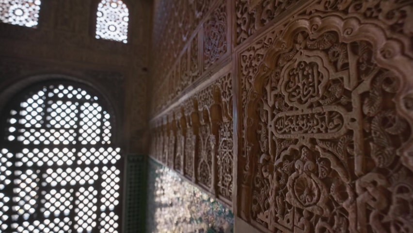 Wall details and Magnificent moorish interior in Alhambra palace, Granada. Camera moves to arches of the window between the walls with Moorish ornaments. Gimbal shot, 4K Royalty-Free Stock Footage #1089017645