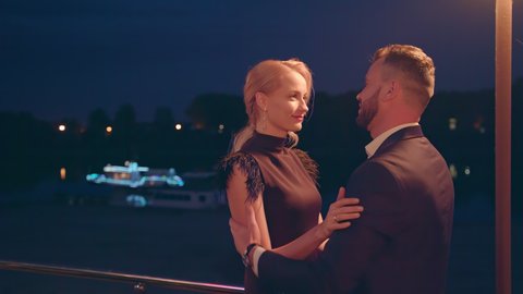 Close up of romantic couple looking in each other's eyes and kissing outdoors in evening. Attractive male and female sharing tender kiss outside at night. 4k. High quality 4k footage