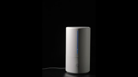 Household humidifier. White electronic device for humidification, ionization and air purification. White water vapor. Steam on a black isolated background.