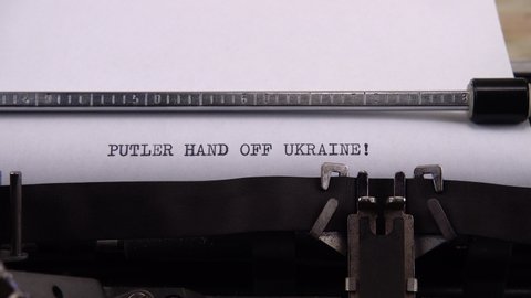 Typing phrase "PUTLER HAND OFF UKRAINE !" on retro typewriter.
