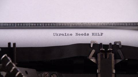 Typing phrase "Ukraine Needs HELP" on retro typewriter.