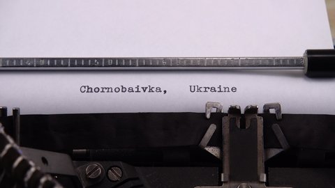 Typing name of village in the Kherson region of Ukraine "Chornobaivka, Ukraine" on retro typewriter.