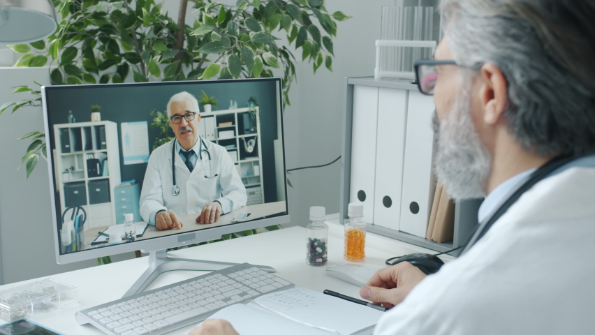 Male colleagues doctors discussing medication holding pills and talking on video call using computer in clinic. Communication and healthcare concept. Royalty-Free Stock Footage #1089025361