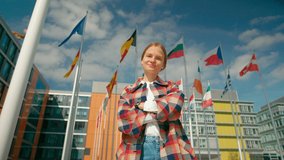 Portrait of Young Woman with Waving Flags of European Union Countries Outside of European Parliament administrative office in Luxembourg City. Politics, Migration and Citizenship concept. 4K hero shot - Powered by Shutterstock - Get 15% off with code: PIKWIZARD15